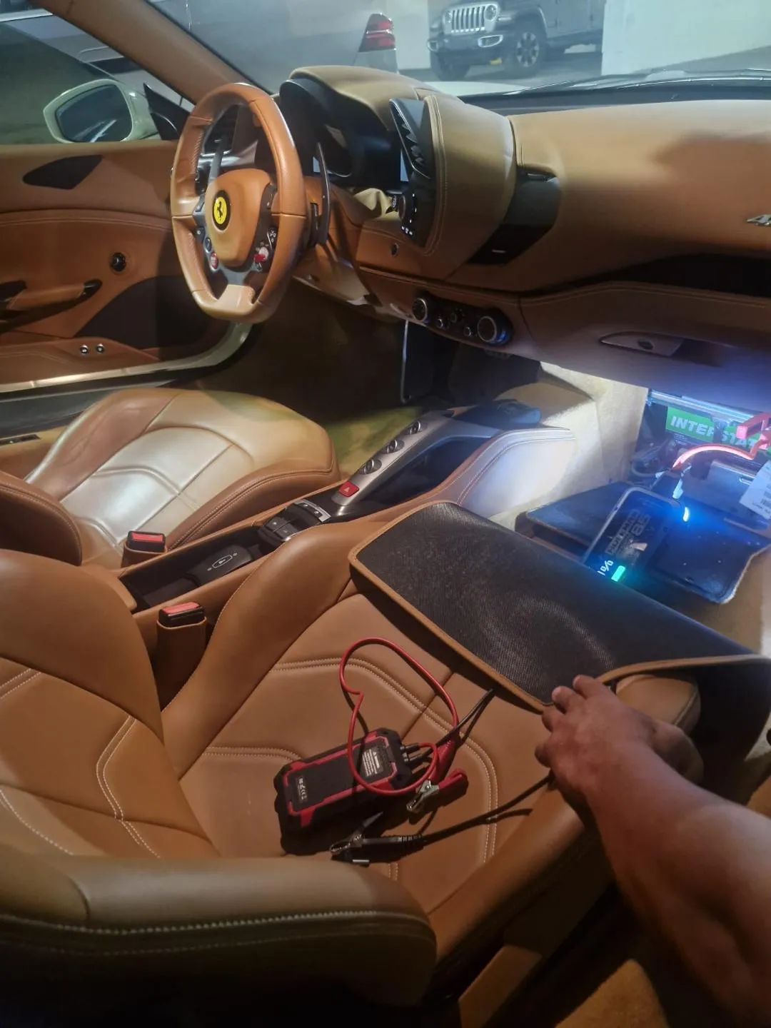 Accessible battery in a Ferrari passenger footwell with service equipment nearby
